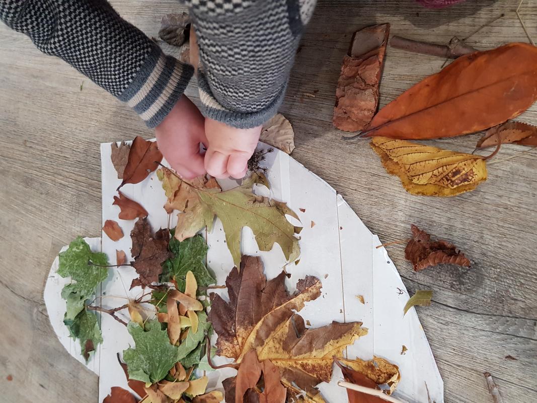 Enfant qui joue avec des feuilles.
